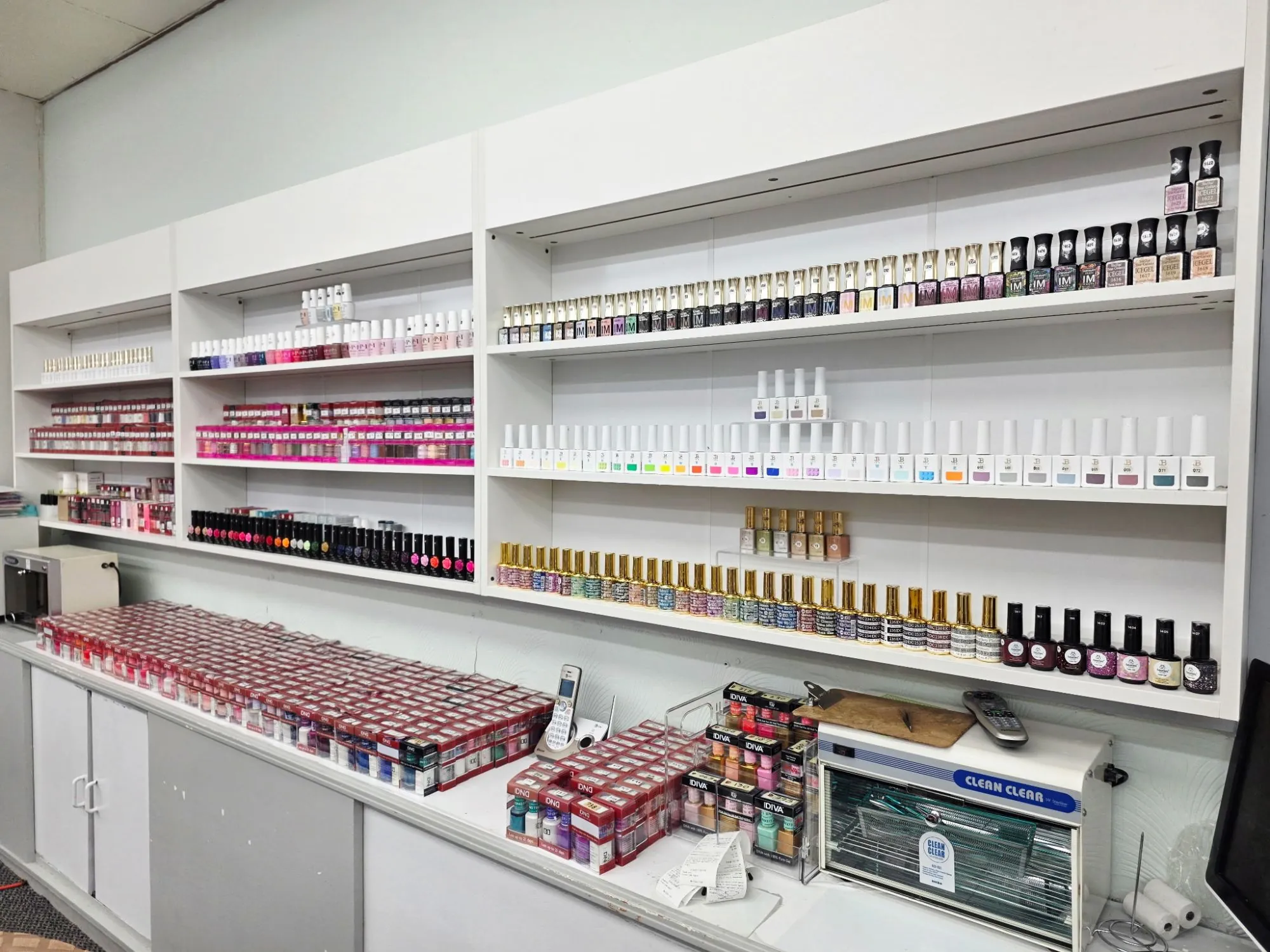 The salon's polish wall: long white shelves lined with hundreds of gel and lacquer colors, from nudes and pinks to brights and glitters